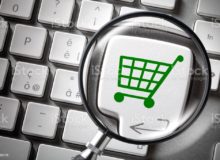 Internet shopping. Financial Planning. Computer keyboard with shopping cart icon key enlarged by a magnifying glass.